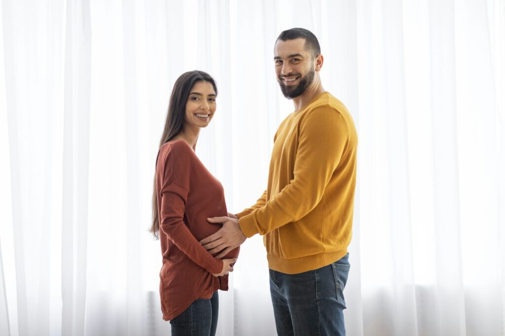 Happy couple touching pregnant belly together